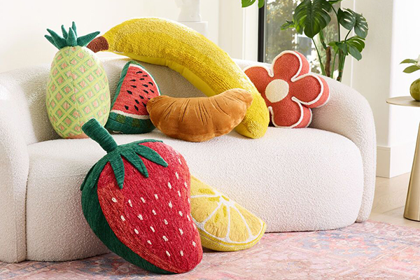 A colorful and uniquely shaped pillow on a modern sofa.