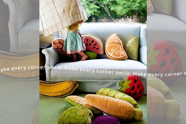 A child and a pet playing together among fun, colorful pillows on the floor.