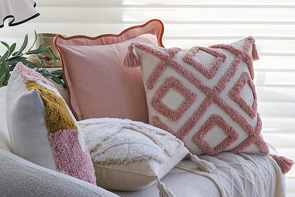 a mix of solid, striped, and textured pillows on a sofa